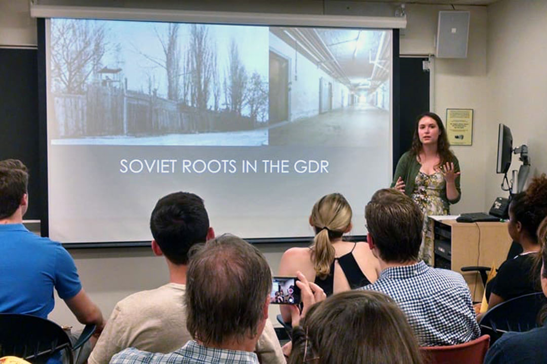 Maggie McCool presenting to a group of students in a classroom with the slide "Soviet Roots in the GDR"