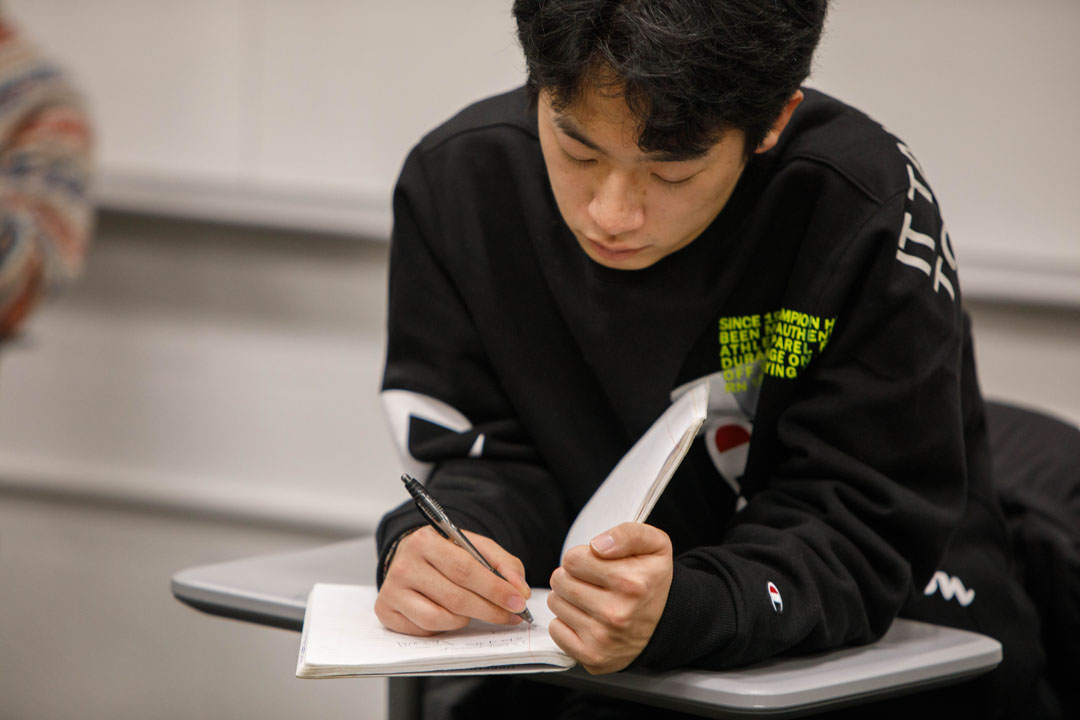 A student writing in a notebook in class