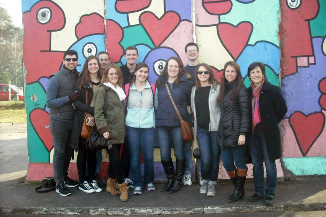 A group of RGSLL students and faculty stand in front of a colorful, abstract mural
