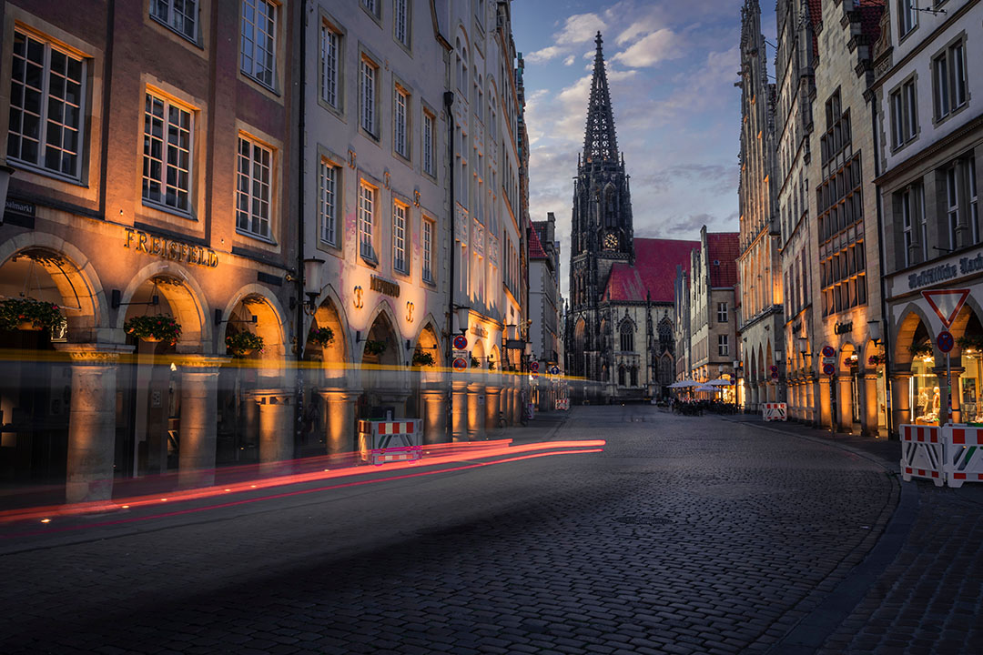 The steeple of a church in Prinzipalmarkt, Munster, Germany, lit up at night